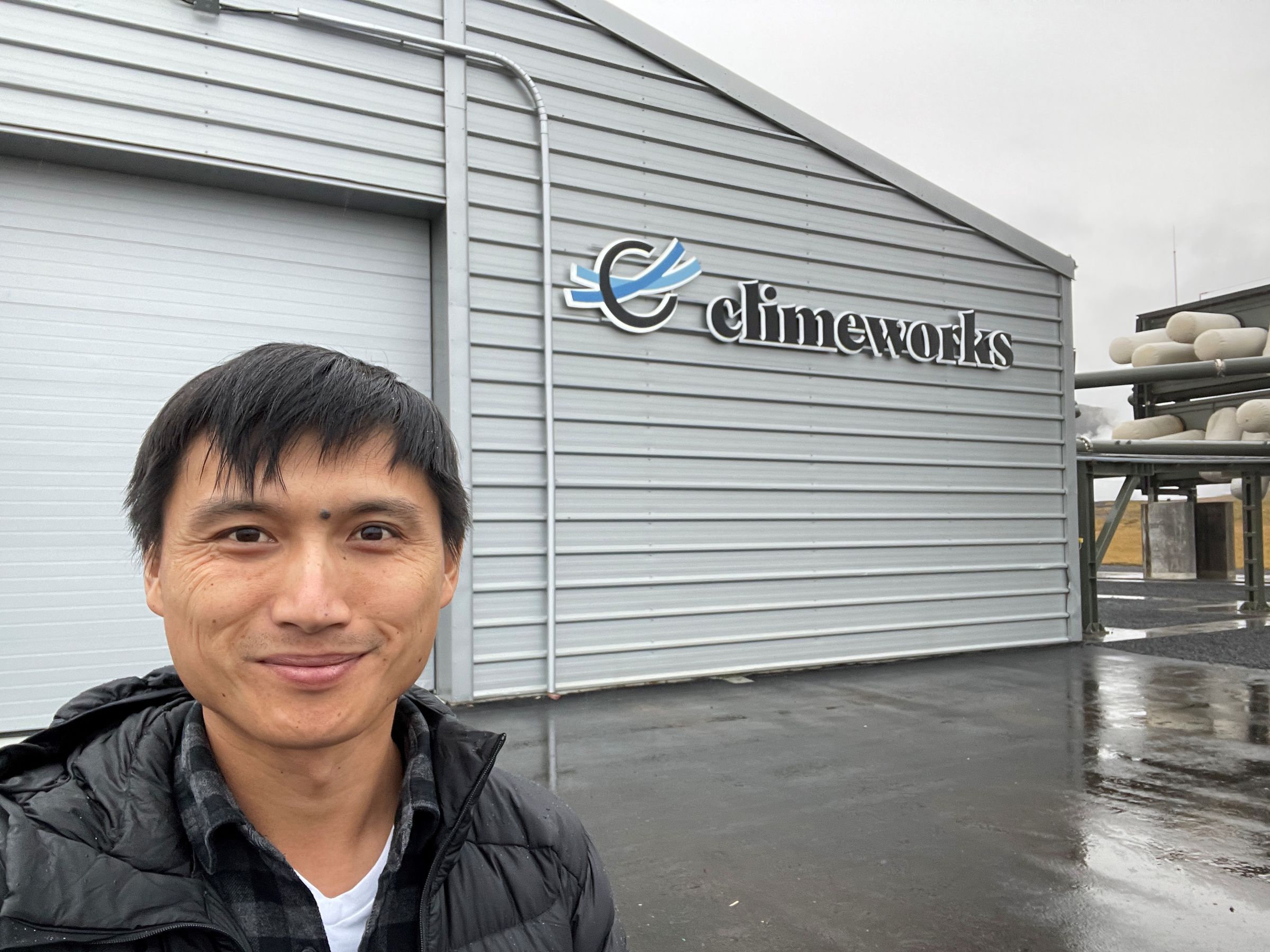 Chan stands in front of a building that says “Climeworks.”
